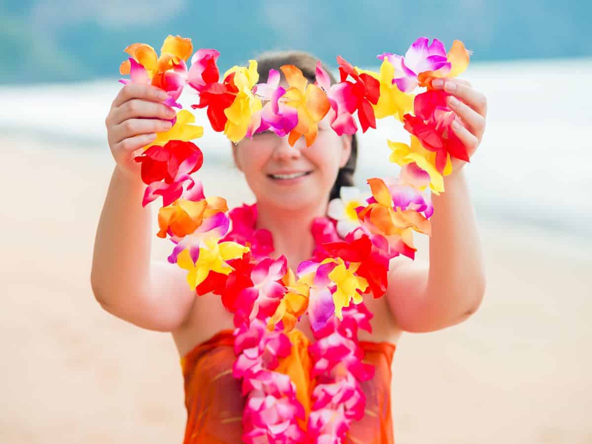 Hawaiian woman greeting luau guests with a floral lei.