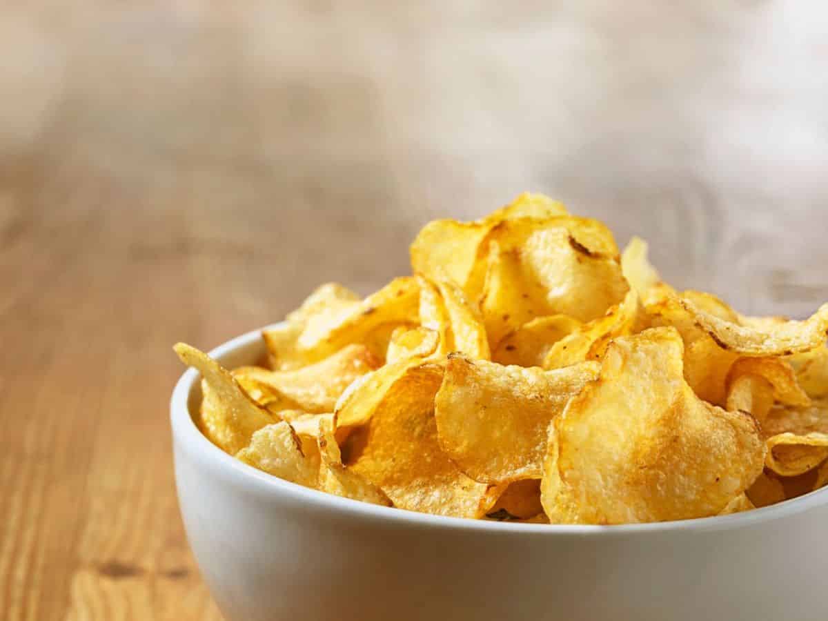A bowl of potato chips on a wooden table.