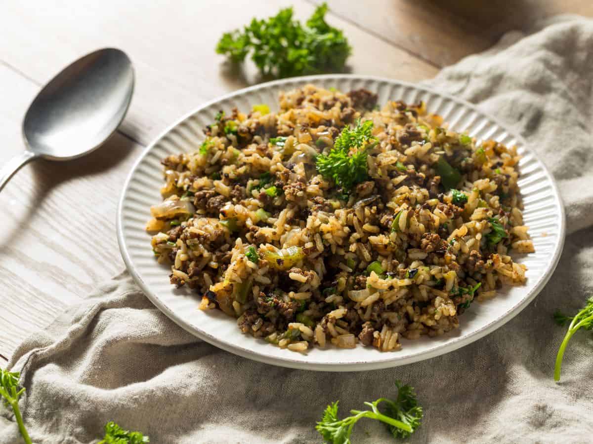 A plate of dirty rice with parsley sprinkled around it.