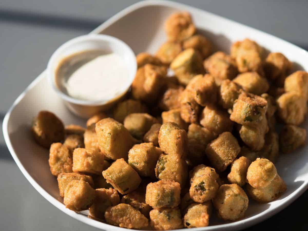 A bowl of fried okra with dipping sauce.