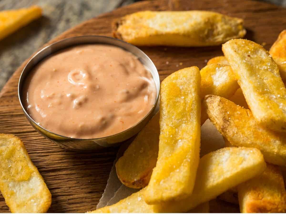 French fries with fry sauce on a wooden cutting board.
