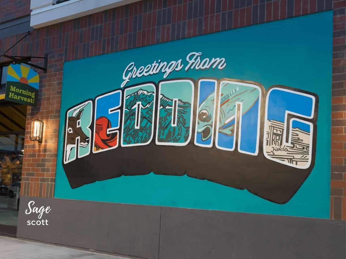 A mural that reads "Greetings from Redding" on a brick walled background.