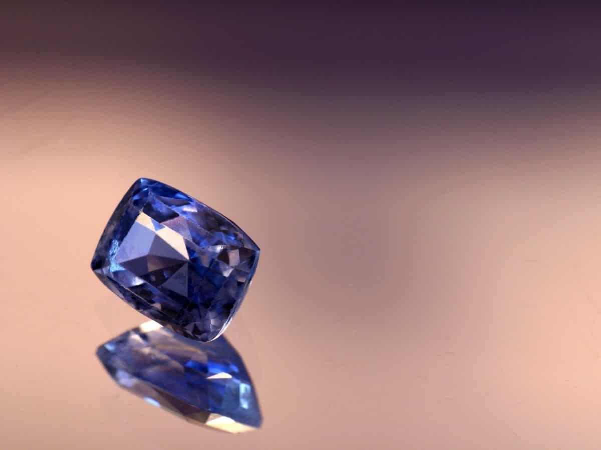 A shimmering blue sapphire sitting on a surface, captivating with its exquisite beauty.
