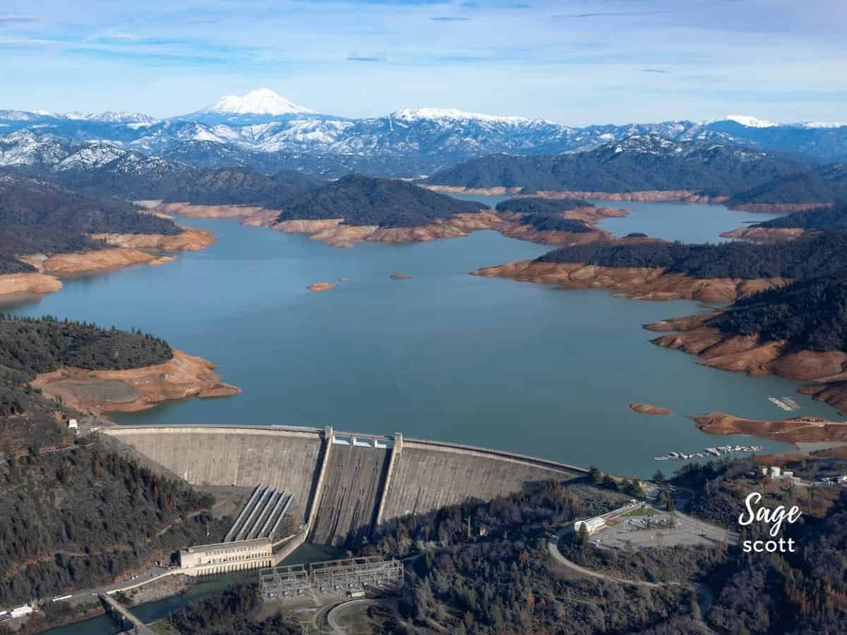 An aerial view of a dam with mountains in the background.