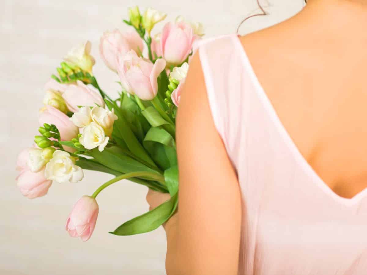 A woman in a light pink dress holding a bouquet of tulips.