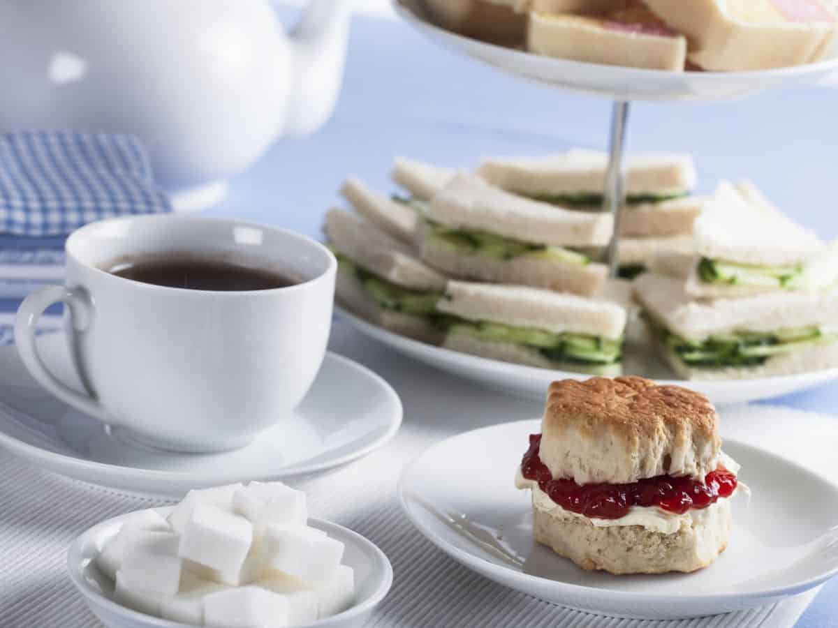 Tea and sandwiches on a plate with a cup of tea.