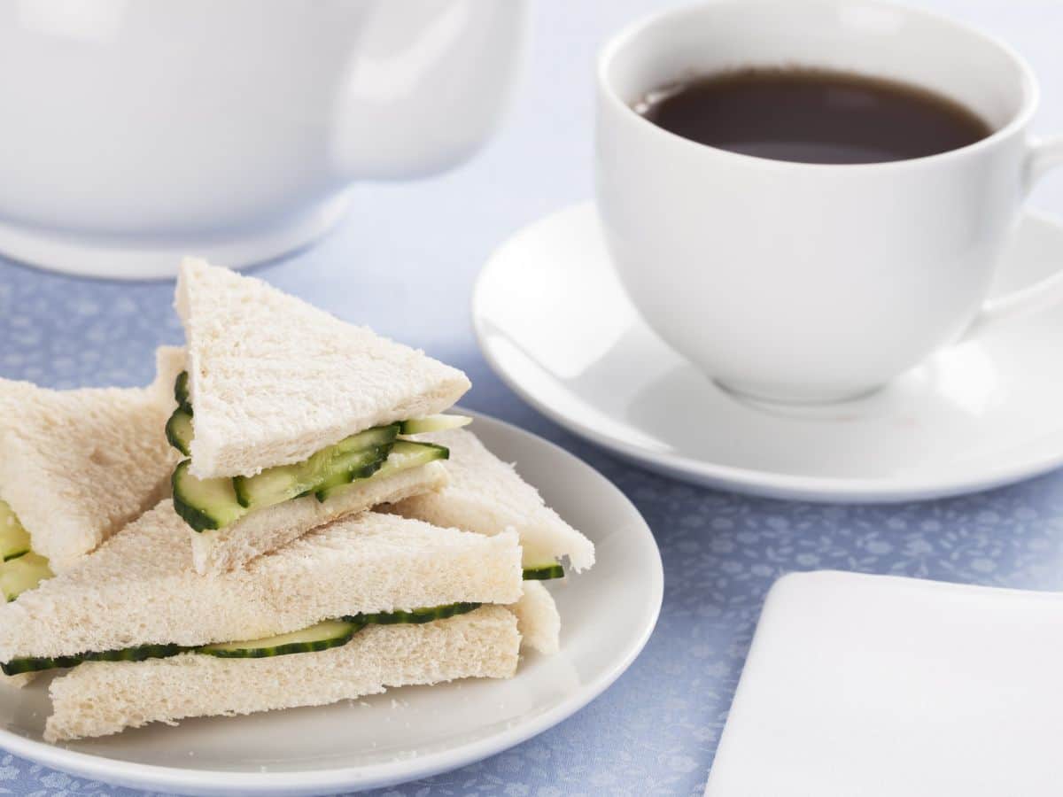 A plate with cucumber sandwiches and a cup of tea.