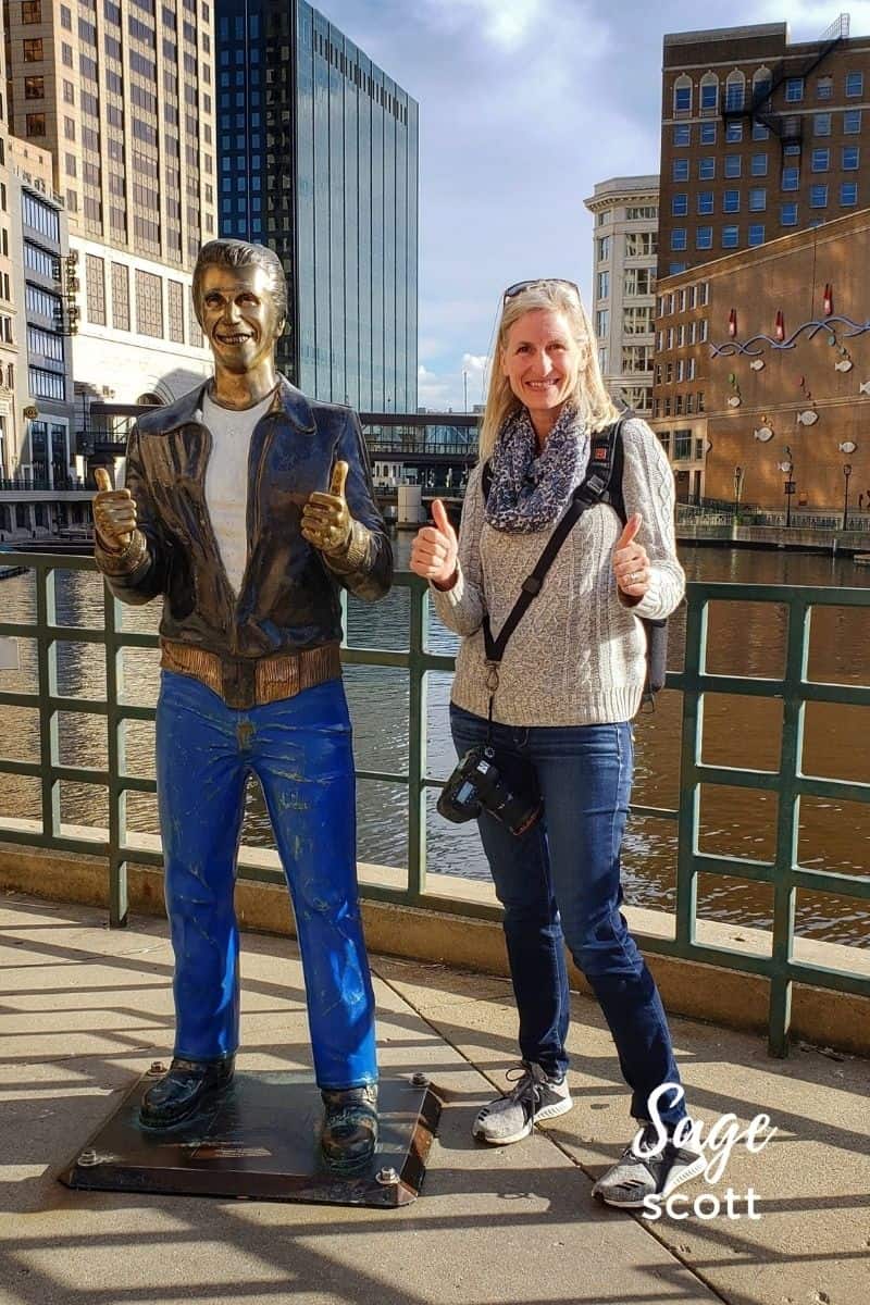 A woman is standing next to a statue of a man.