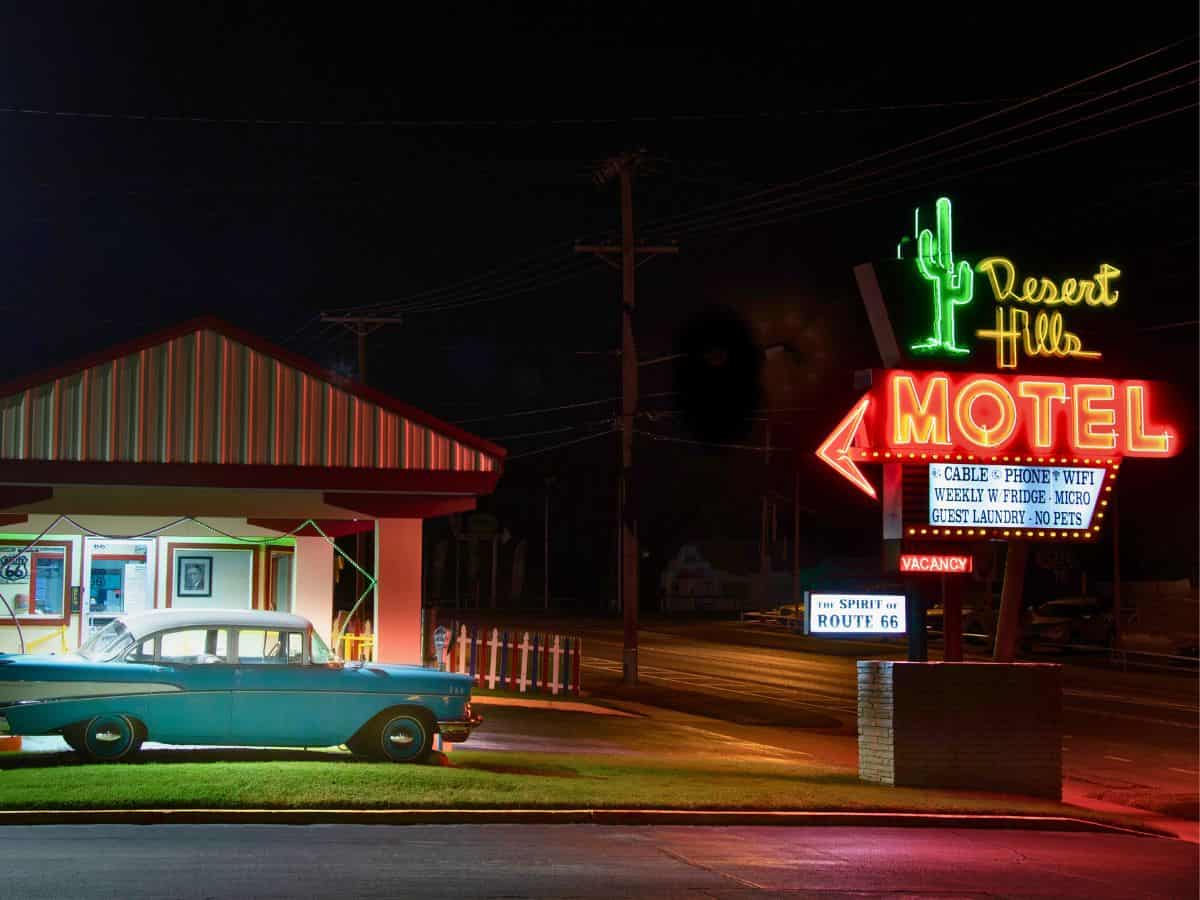 A classic car sits in front of a the neon sign of the Desert Hills Motel along Route 66 in Tulsa, OK.
