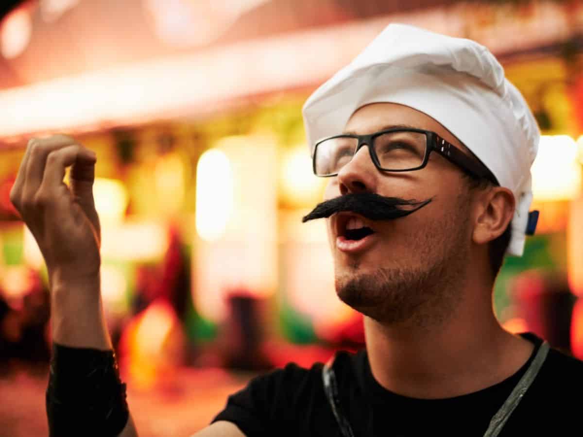 A man wearing a chef hat with a mustache.