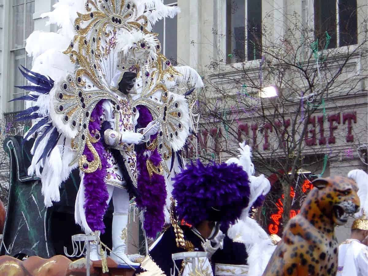 A man in a king costume on a float in a Mardi Gras parade.