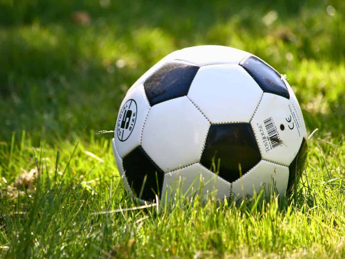 A black and white soccer ball sitting in a grassy field.