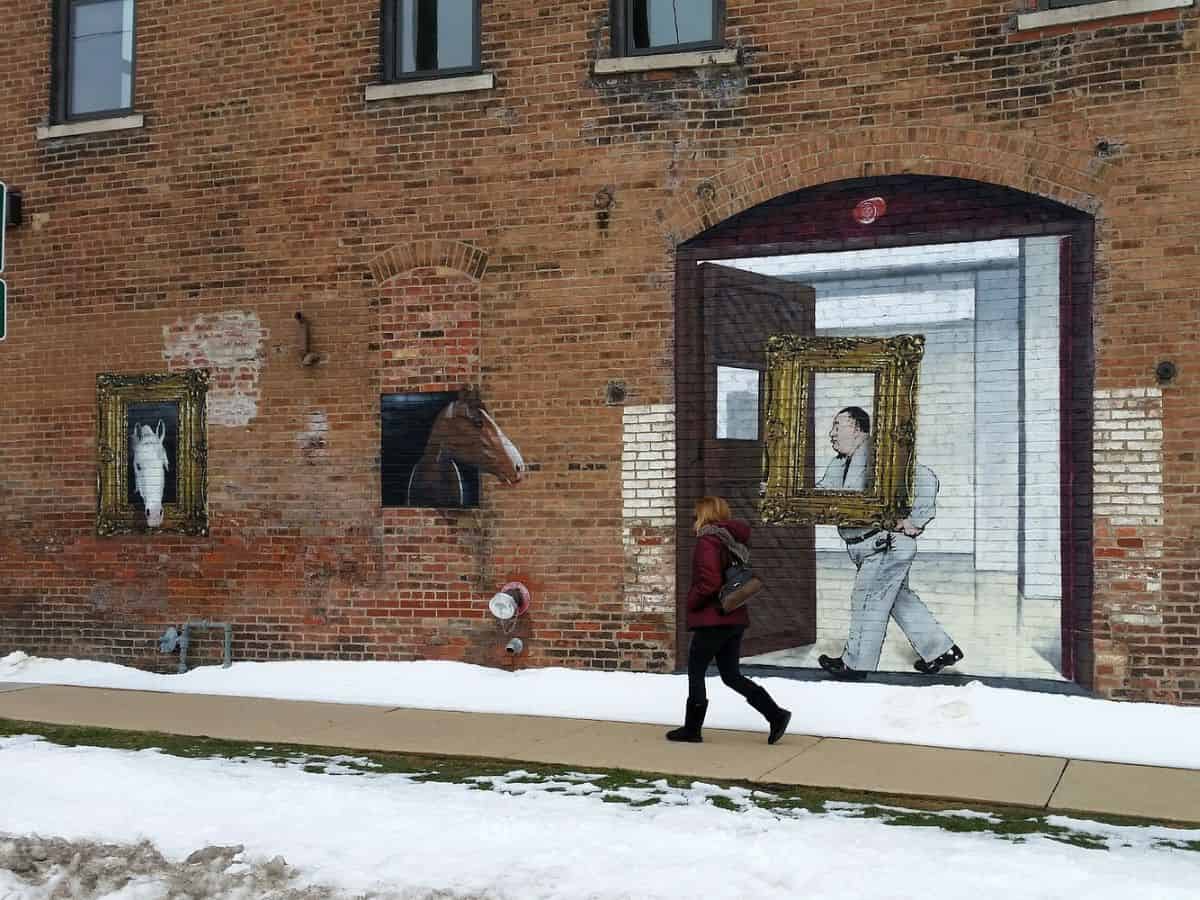 A woman walks past a building with a mural on it in Bloomington, IL.