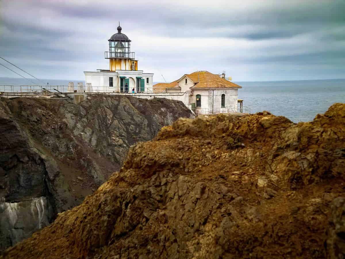 A lighthouse on a craggy cliff overlooking the Pacific Ocean.