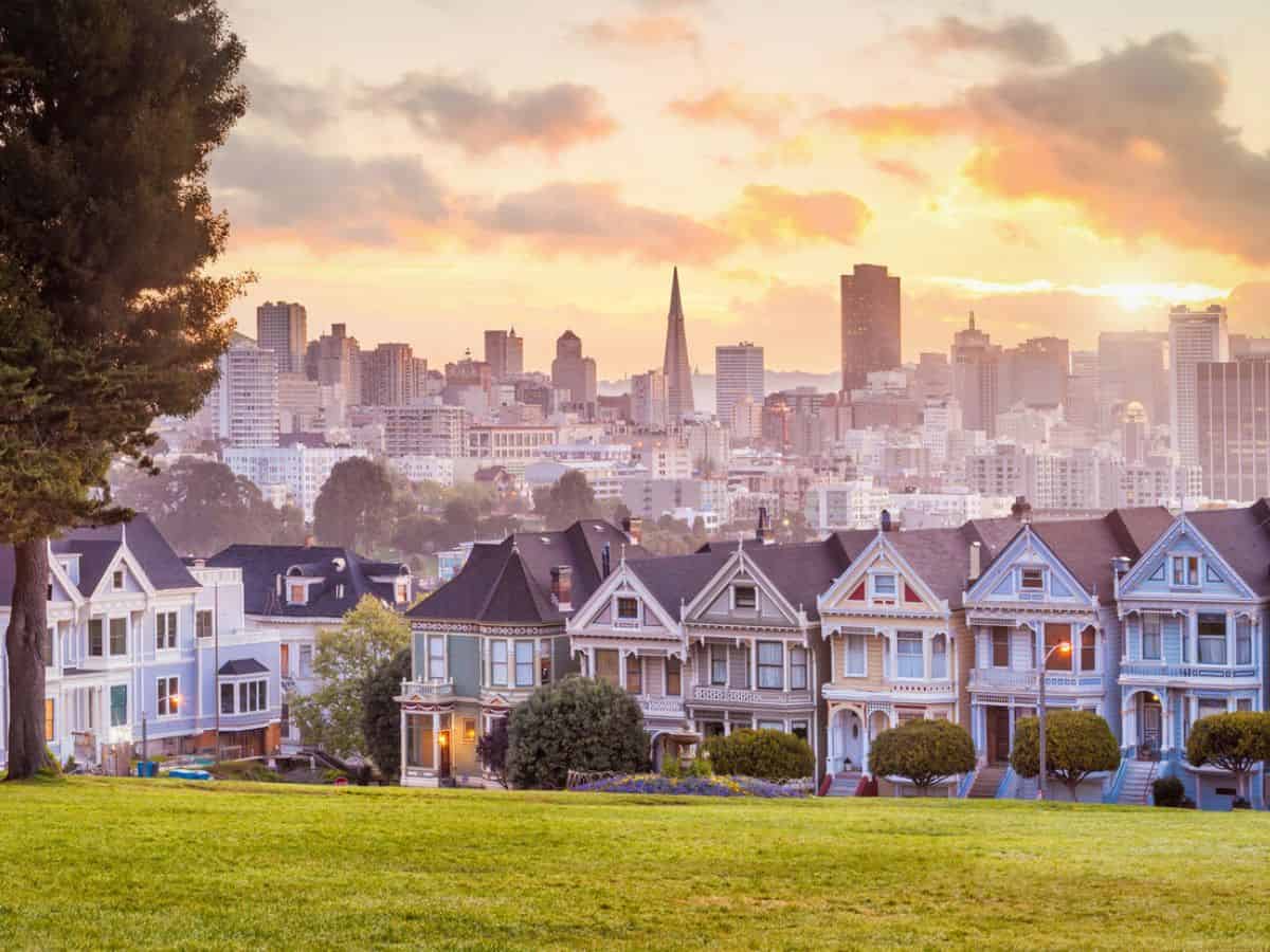 A row of Victorian houses in Alamo Square with the San Francisco skyline in the background.