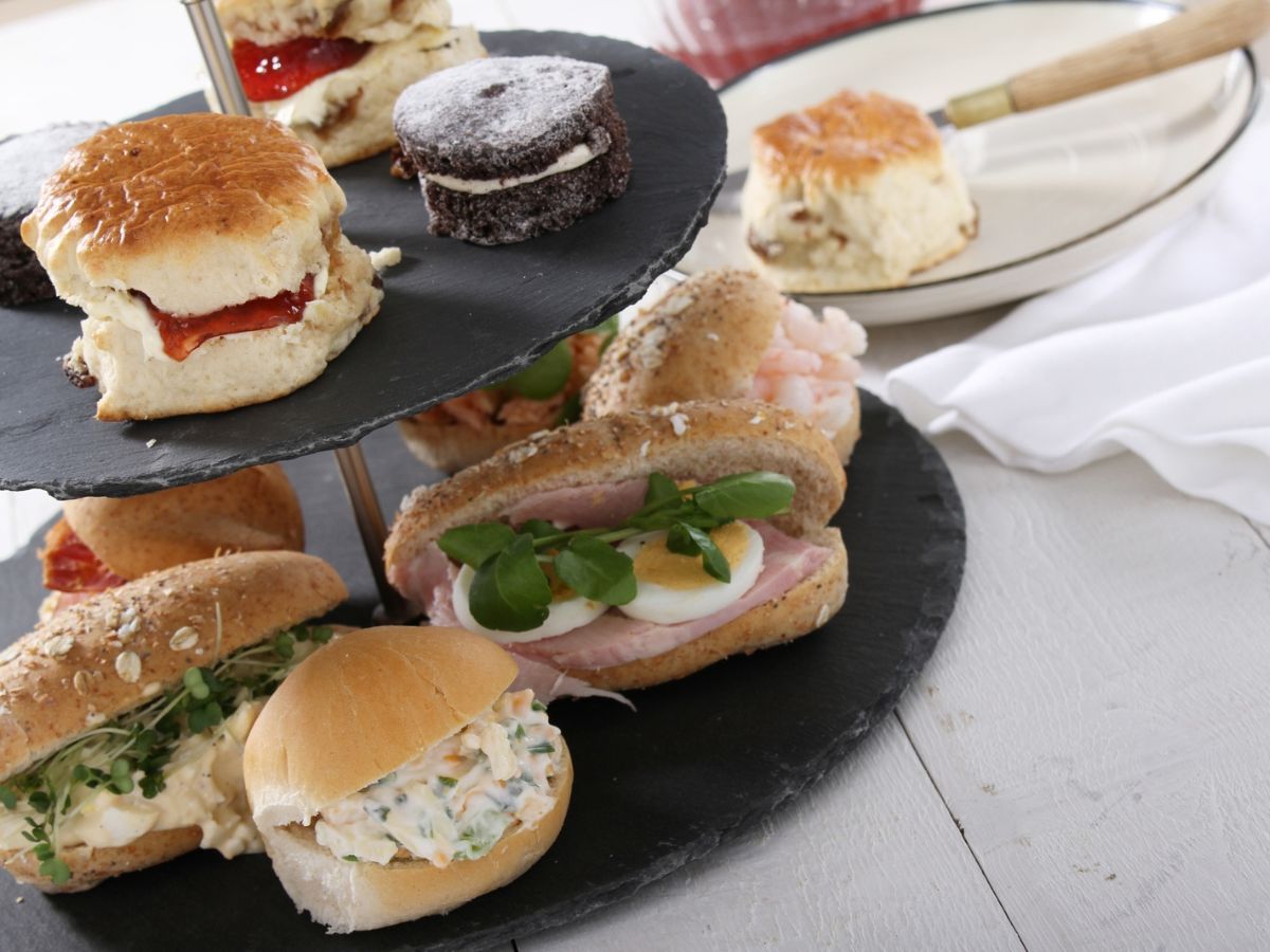 An assortment of sandwiches and scones displayed on a tiered serving stand.