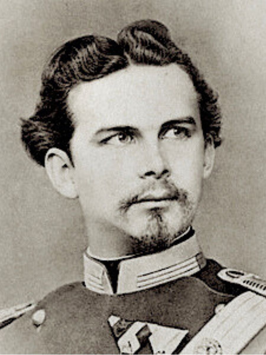 Black and white portrait of a man in a military uniform with epaulettes, featuring wavy hair, a mustache, and a trimmed beard.