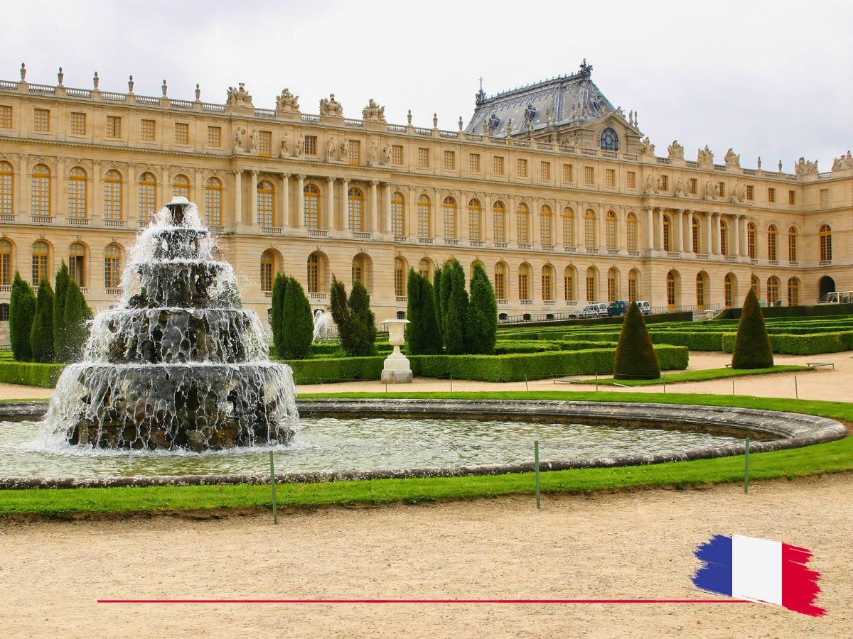 The image shows the Palace of Versailles with a large fountain in the foreground and manicured gardens. A small French flag design is in the bottom corner.